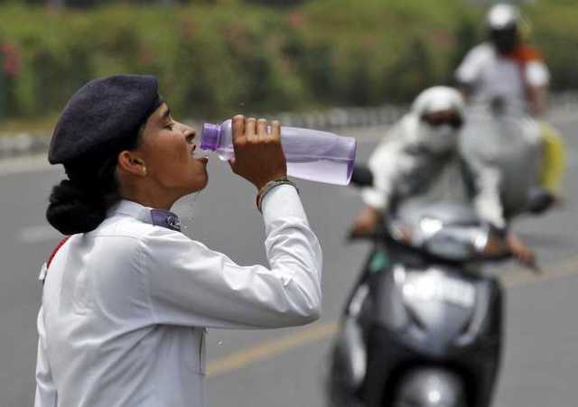 A traffic police woman drinks water as commuters drive along a road on a hot summer day in Chandigarh, India, May 31, 2015. While temperatures regularly top 40 degrees Celsius (104 degrees Fahrenheit) in May and June, parts of the south and east of India have baked under heat as high as 47 degree Celsius for seven straight days. REUTERS/Ajay Verma